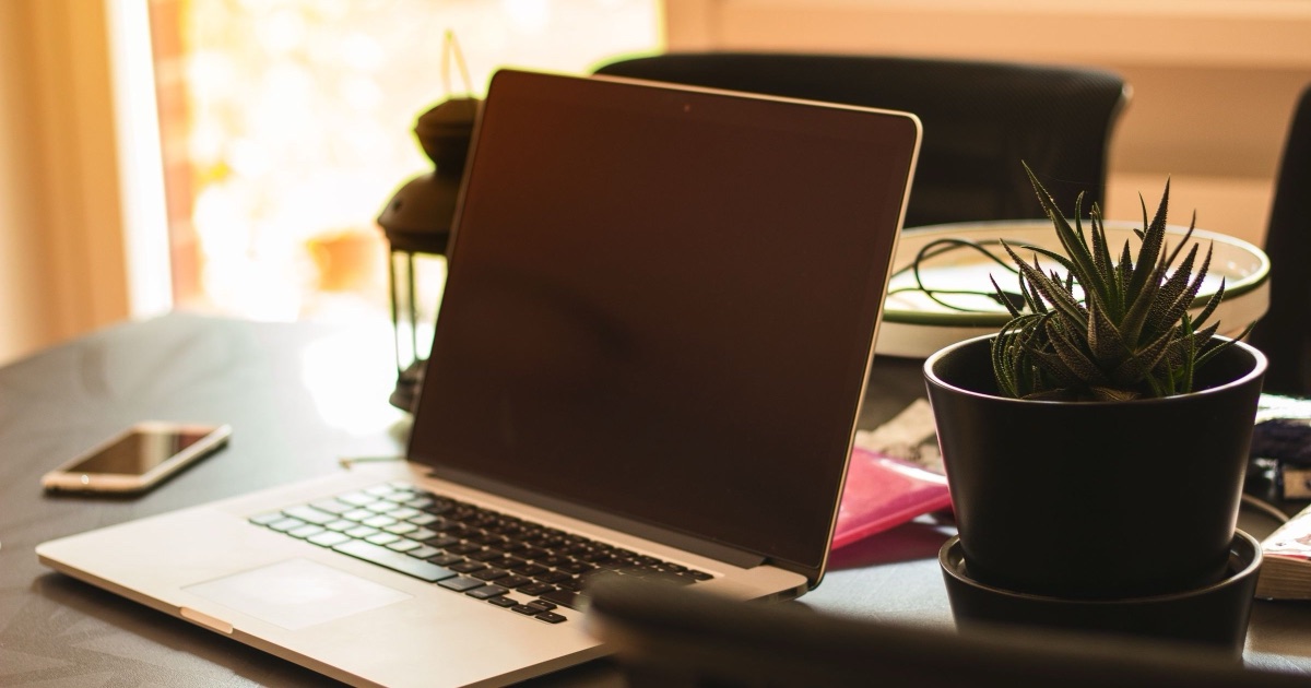 Open laptop and phone on a wooden desk, the setup a Canadian therapist uses to compare email options